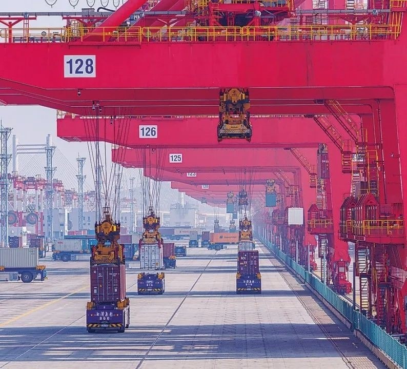 共建“一帶一路”國家在工作制度對接、技術標準協(xié)調、檢驗結果互認等方面強化合作、統(tǒng)一標準，貿易自由化便利化水平不斷提升。上海洋山港海關對接共建國家進出口貨物相關標準，推動通關一體化方式申報，提升通關效率。圖為無人駕駛的全自動導引車在洋山港穿梭往來，搬運集裝箱。王初 攝