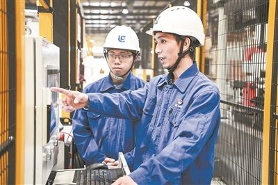 在廣西柳工機(jī)械股份有限公司生產(chǎn)車間內(nèi)，一名高級技師（右）給徒弟講解數(shù)控設(shè)備操作細(xì)節(jié)。新華社記者 曹祎銘攝