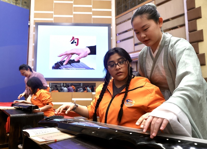 2024年3月20日，美國華盛頓州中學(xué)生代表團(tuán)北京大學(xué)交流活動(dòng)在北京大學(xué)英杰交流中心舉行。圖為來自華盛頓州的中學(xué)生體驗(yàn)古琴。