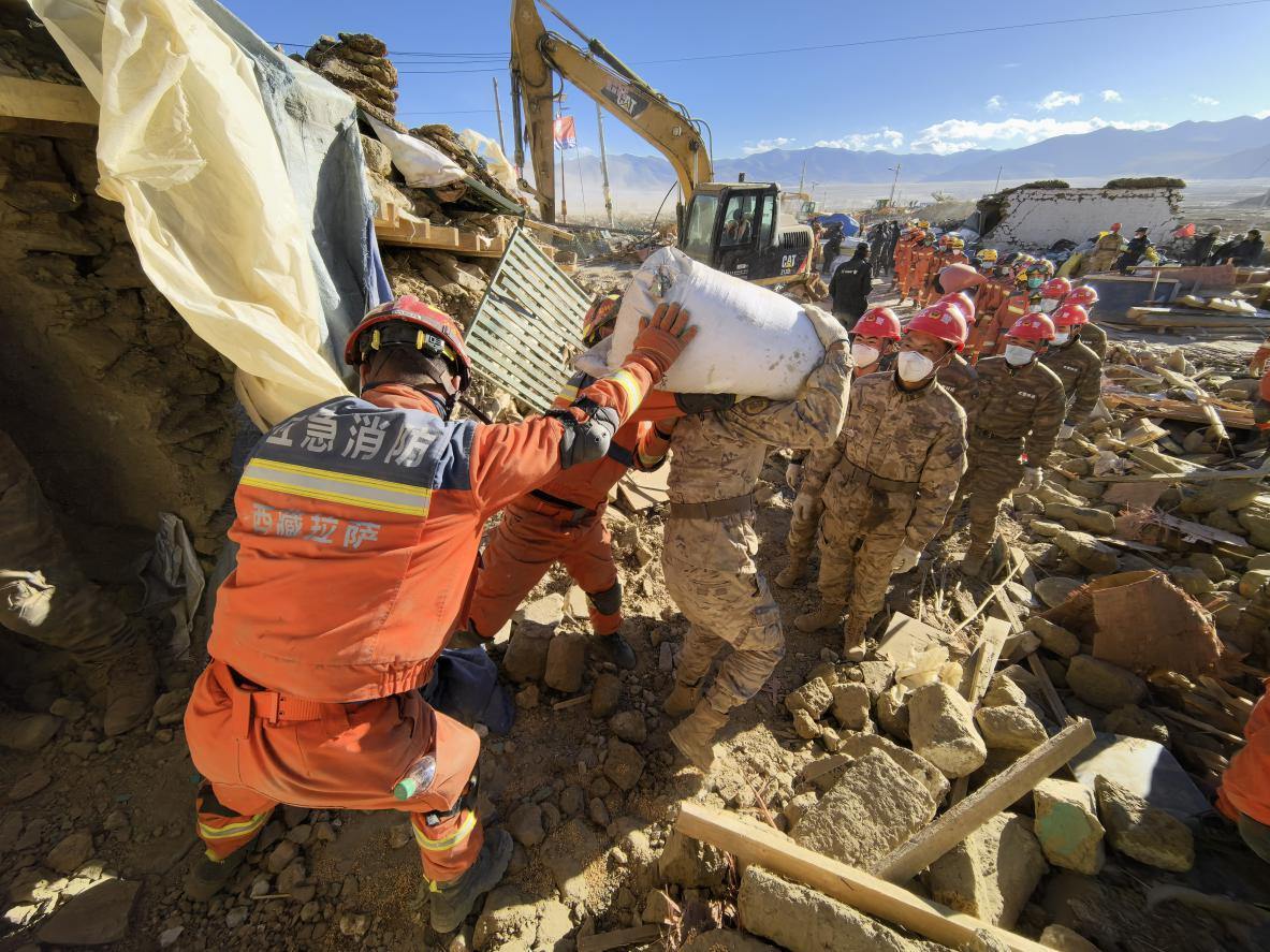 1月11日，定日縣長所鄉(xiāng)古榮村，應(yīng)急消防等救援人員排隊接力搶運掩埋在倒塌房屋下的群眾財物。人民日報記者楊翹楚攝