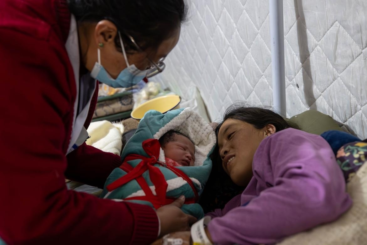 1月10日，定日縣中心醫(yī)院的婦產(chǎn)科醫(yī)生悉心照看一位母親和她懷里的新生兒。人民日報記者張武軍攝