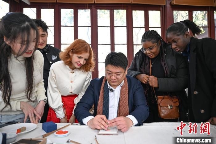 1月20日，篆刻家王臻向外籍留學(xué)生展示篆刻印章。當日，來自巴西、馬來西亞、加納、哈薩克斯坦的外籍留學(xué)生在浙江杭州西泠印社體驗福貼、春聯(lián)和篆刻，感受古老的中國傳統(tǒng)文化。中新社記者 王剛 攝