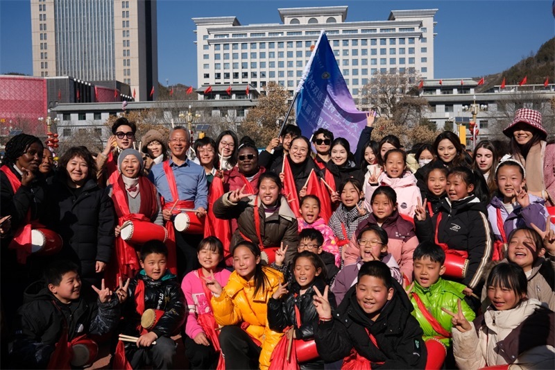 中外青年學(xué)子在安塞文化廣場(chǎng)觀看陜北腰鼓和大秧歌表演后合影留念，大家踏著鼓點(diǎn)共舞，翻飛的紅綢與躍動(dòng)的身影交織，在黃土地廣場(chǎng)上繪出一幅生動(dòng)的陜北民俗互動(dòng)畫(huà)卷