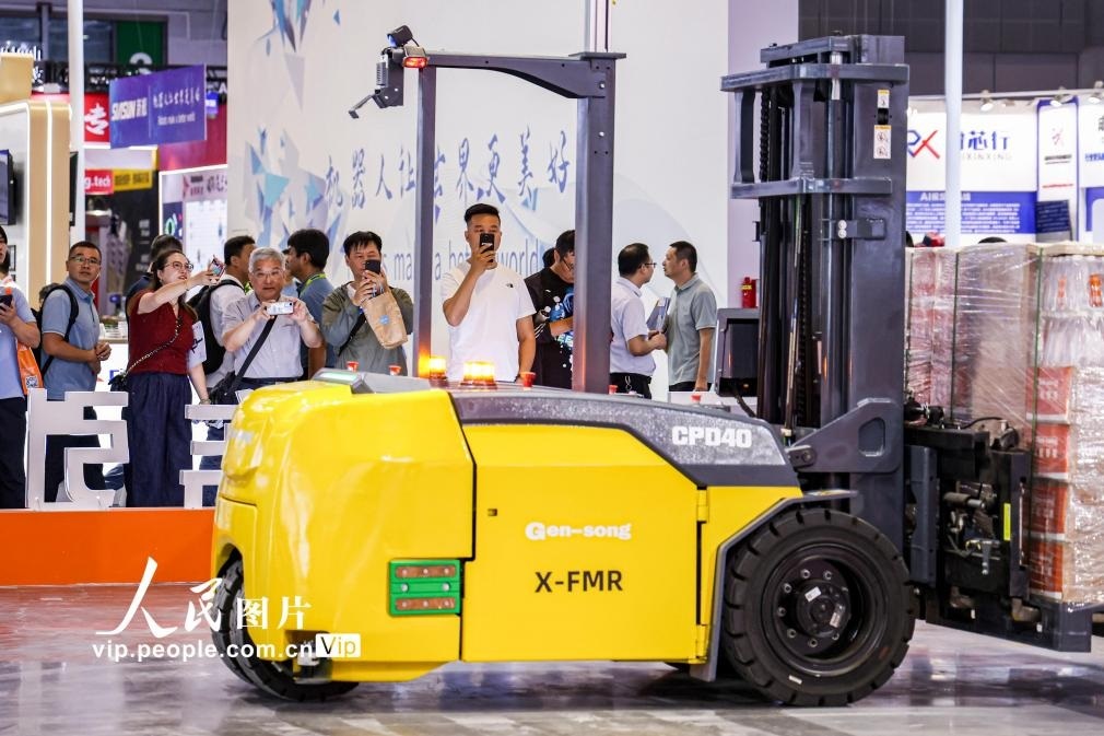 第24屆中國工博會現(xiàn)場，觀眾觀看叉取機器人作業(yè)演示。王初攝（人民圖片網）