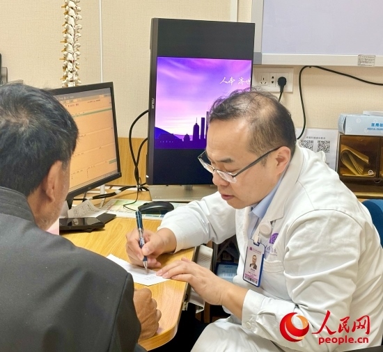 路桂軍接診時(shí)為患者寫下用藥提示。人民網(wǎng)記者 金慧慧攝