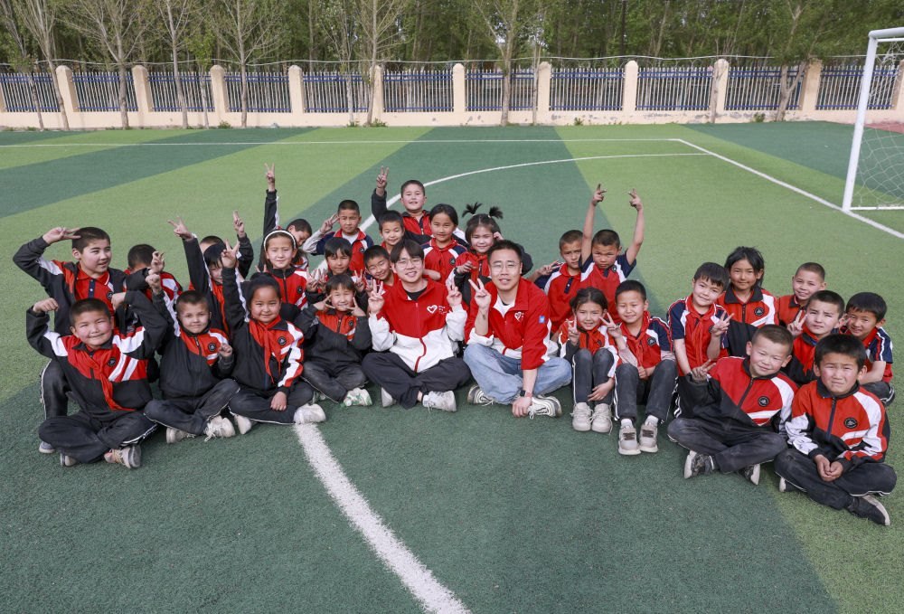 4月23日，在新疆克州阿圖什市哈拉峻鄉(xiāng)謝依特小學(xué)，支教教師王俊文（中左）、李軻凡（中右）和學(xué)生在一起。