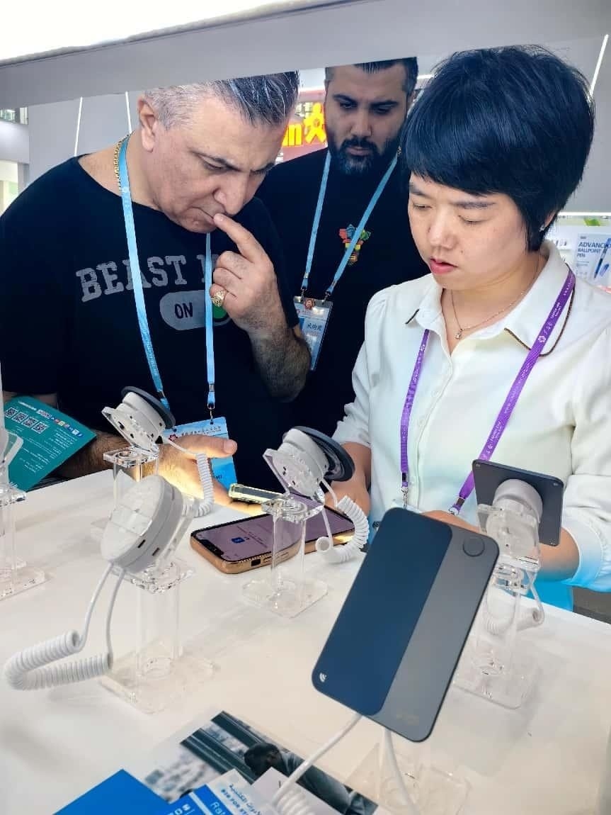 展臺(tái)工作人員向外商展示“AI TOP翻譯終端”。圖片來(lái)源：受訪(fǎng)者提供