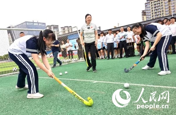 陳朝霞（中）指導(dǎo)學(xué)生體驗曲棍球。 人民網(wǎng)記者 楊磊攝